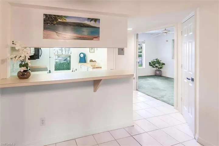 Kitchen featuring a kitchen bar, kitchen peninsula, light tile patterned floors, and ceiling fan
