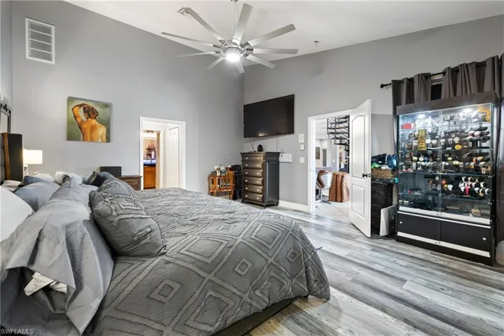 Bedroom with light wood finished floors, a ceiling fan, lofted ceiling, and a barn door