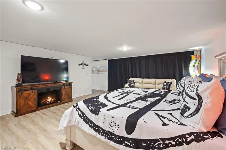 Bedroom featuring a lit fireplace, light wood finished floors, and recessed lighting