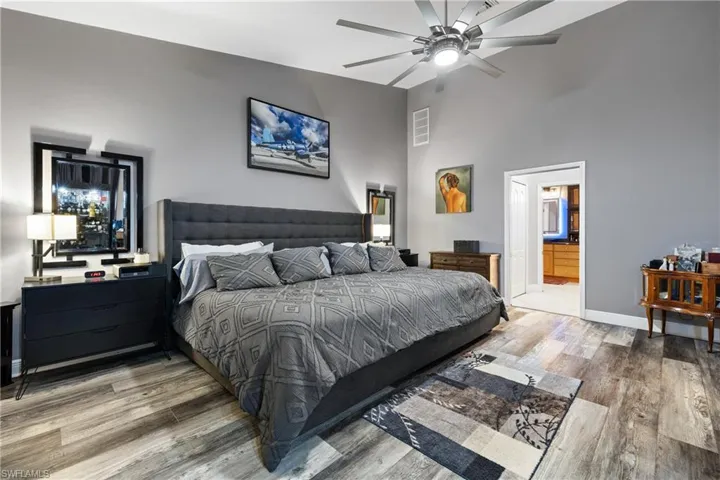 Bedroom with light wood-style floors, a ceiling fan, and ensuite bathroom