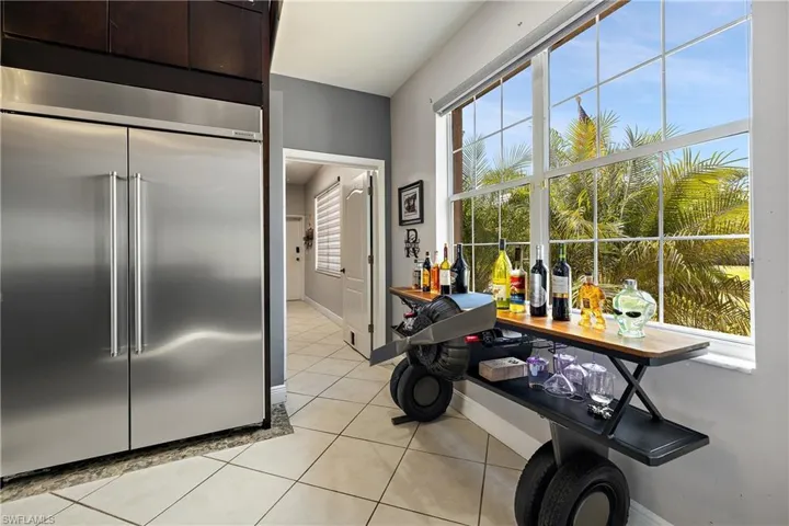 Kitchen with built in fridge, light tile patterned flooring, and dark wood finish cabinetry