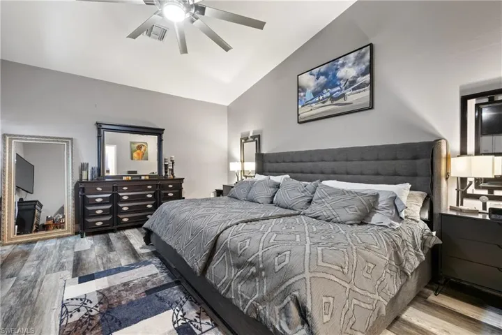 Bedroom with vaulted ceiling, wood finished floors, and ceiling fan