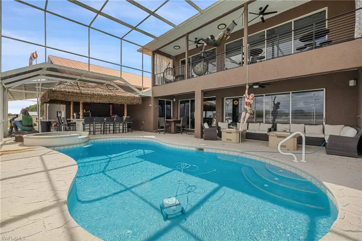 Integrated pool / hot tub with an outdoor lounge area with bar, a patio, a lanai, a balcony, and a sunroom
