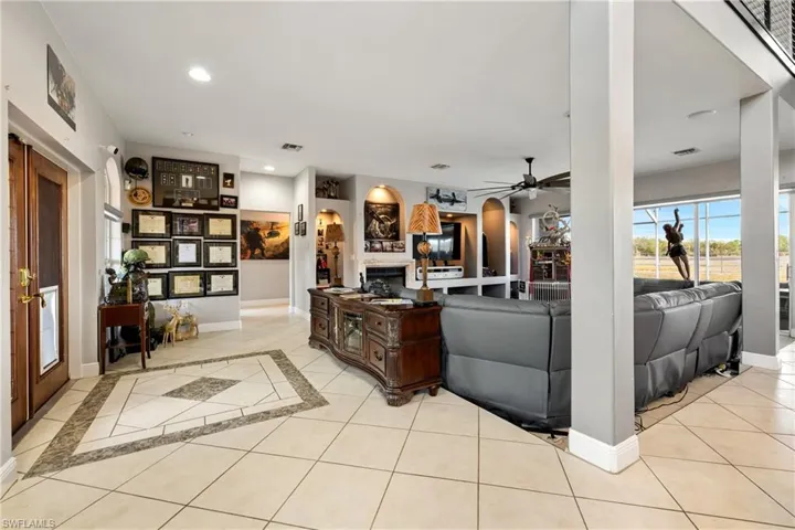 Living room featuring plenty of natural light, light tile patterned flooring, arched walkways, a ceiling fan, and recessed lighting