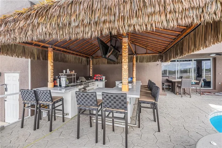 View of patio featuring a grill, an outdoor bar and dining area, and an outdoor pool