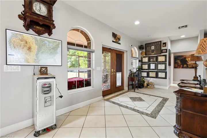 Entryway featuring light tile patterned floors, french doors, inlaid floor details, and recessed lighting