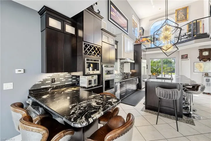 Kitchen with a breakfast bar, a center island, pendant lighting, glass fronted cabinets, and a peninsula