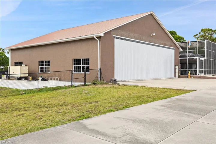 View of side of home featuring stucco siding, a garage, and an outbuilding
