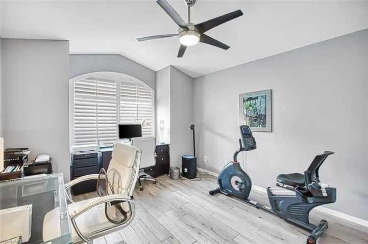 Office space featuring ceiling fan, light wood-style flooring, and vaulted ceiling