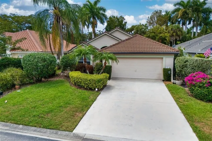 View of front of property with a garage, a tiled roof, driveway, stucco siding, and a front yard