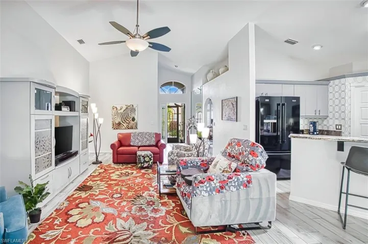 Living area with lofted ceiling, ceiling fan, and light wood-style flooring