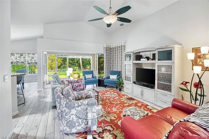Living area featuring a ceiling fan, light wood finished floors, and lofted ceiling