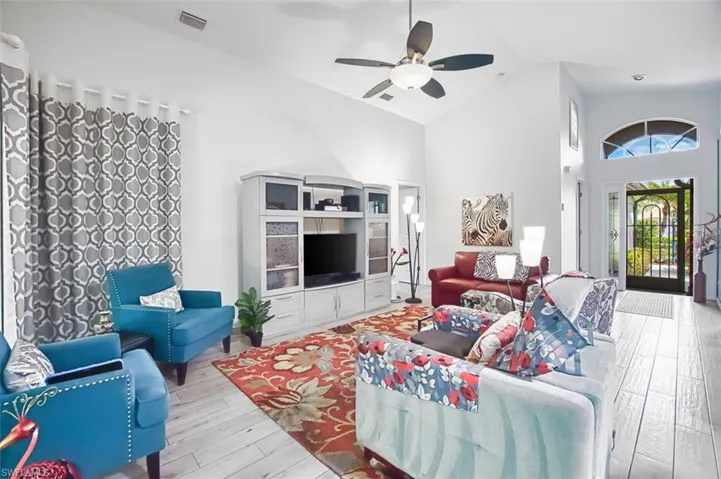 Living area featuring light wood finished floors, a ceiling fan, and vaulted ceiling