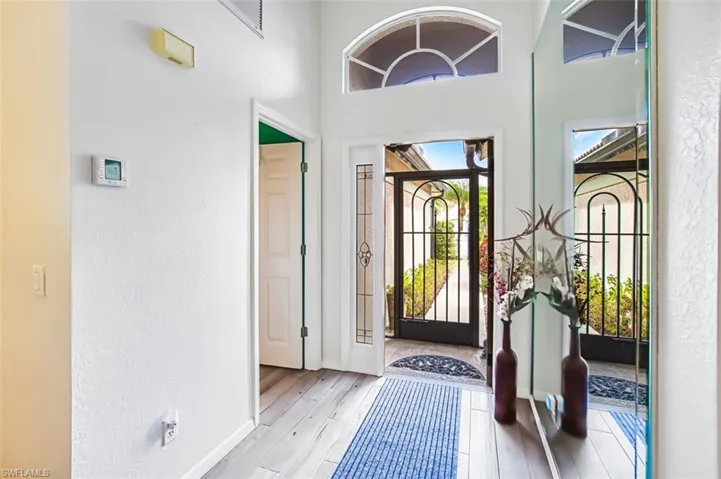 Entryway featuring light wood finished floors, a high ceiling, and a textured wall