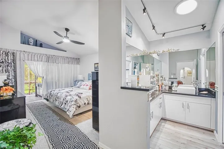 Bedroom with lofted ceiling, light wood-style flooring, a ceiling fan, rail lighting, and access to exterior