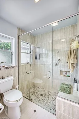 Bathroom with tile walls, a shower stall, and light tile patterned flooring