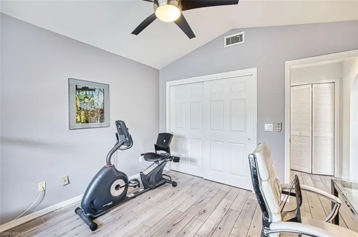 Workout area with light wood-style flooring and ceiling fan