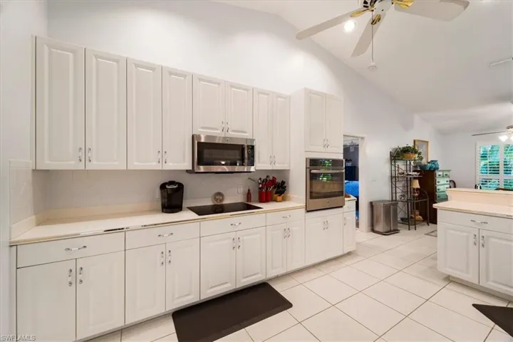 Kitchen featuring ceiling fan, stainless steel appliances, backsplash, and white cabinetry