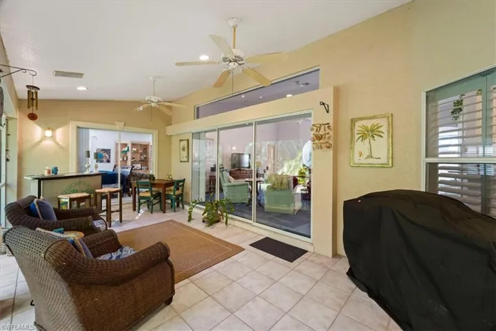 Living room featuring ceiling fan, vaulted ceiling, and light tile flooring