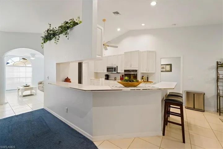 Kitchen with light tile flooring, a breakfast bar area, ceiling fan, and stainless steel appliances