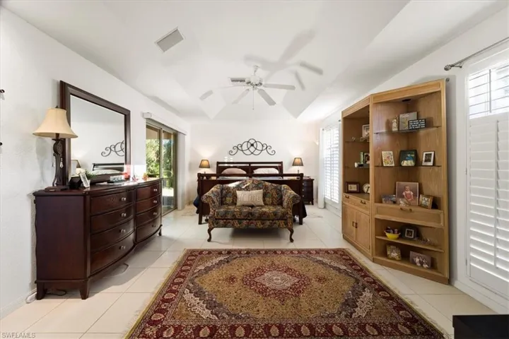 Tiled bedroom featuring ceiling fan, multiple windows, and a raised ceiling