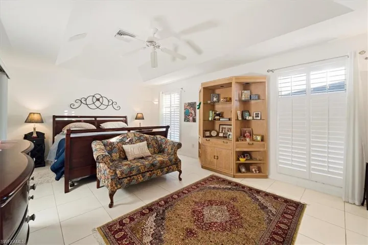Bedroom featuring a raised ceiling, ceiling fan, and light tile floors