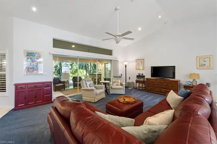 Living room featuring high vaulted ceiling, ceiling fan, and dark carpet