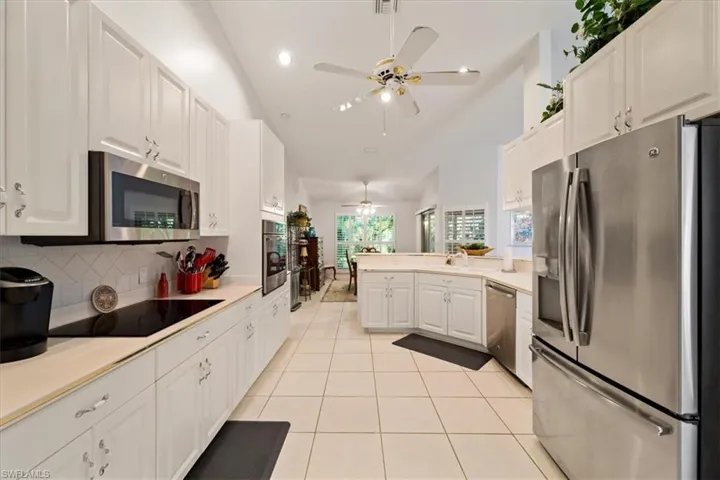 Kitchen featuring ceiling fan, tasteful backsplash, white cabinetry, appliances with stainless steel finishes, and light tile floors