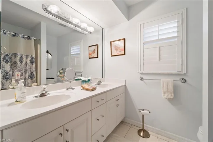 Bathroom featuring tile floors, toilet, double sink, and oversized vanity