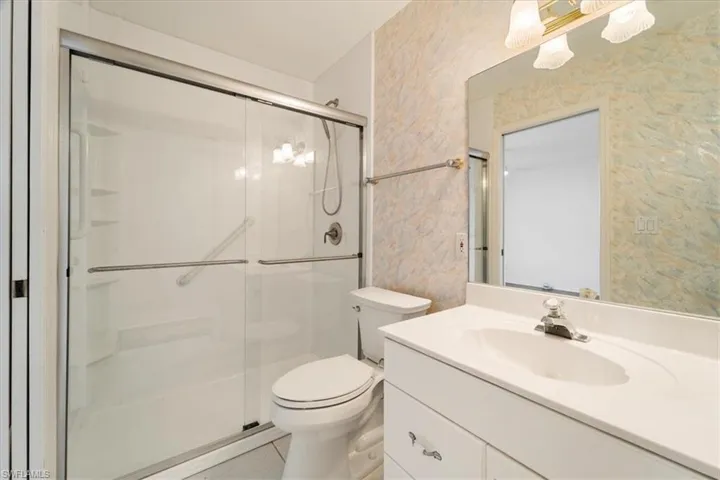 Bathroom featuring tile floors, vanity with extensive cabinet space, an enclosed shower, and toilet