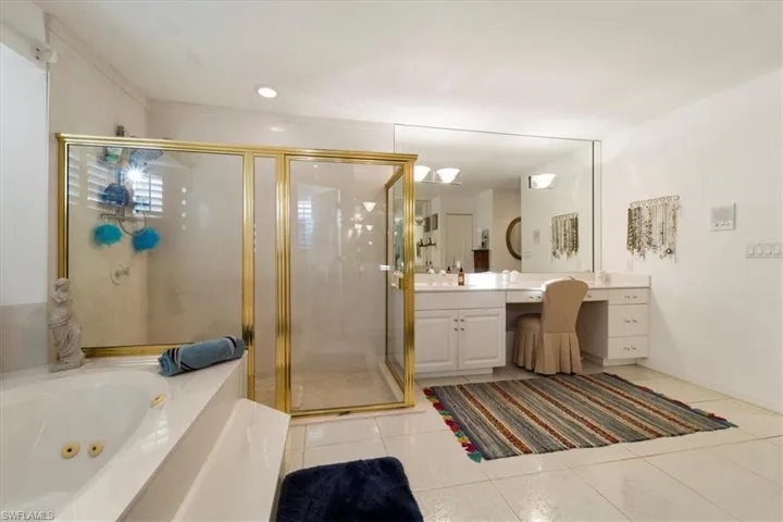 Bathroom featuring tile flooring, shower with separate bathtub, and vanity
