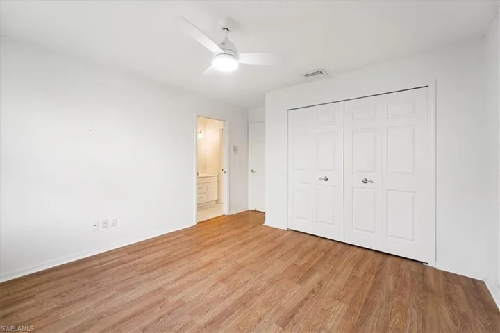 Unfurnished bedroom with a closet, ceiling fan, light hardwood / wood-style floors, and connected bathroom