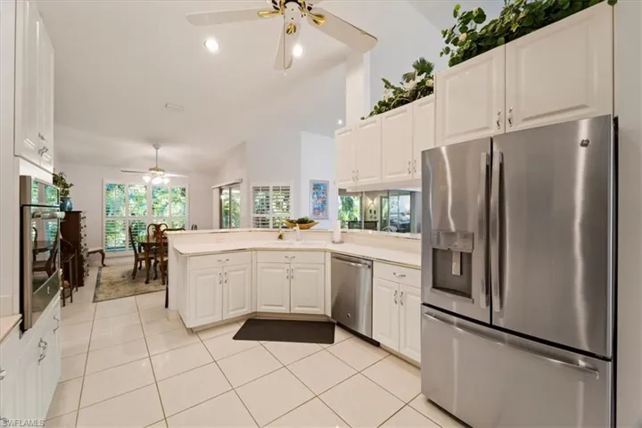 Kitchen with stainless steel appliances, white cabinets, ceiling fan, and kitchen peninsula