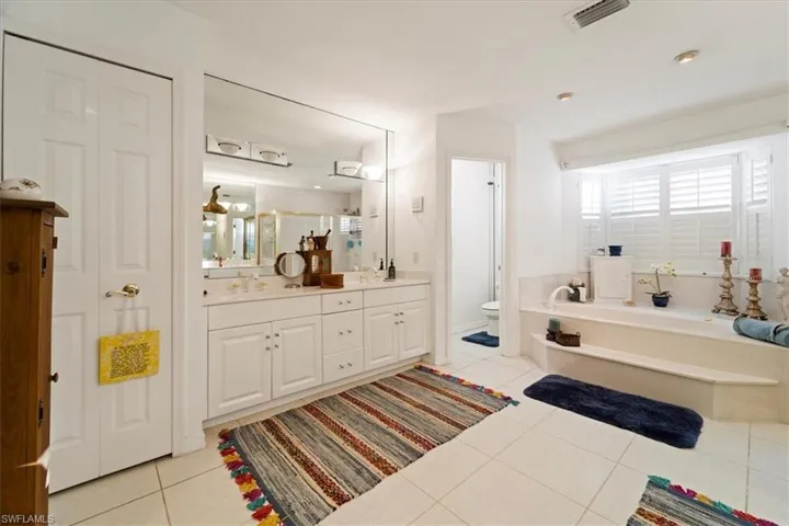 Bathroom with a tub, double vanity, toilet, and tile floors