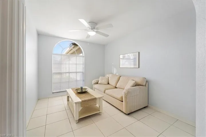 Living room with ceiling fan and light tile floors