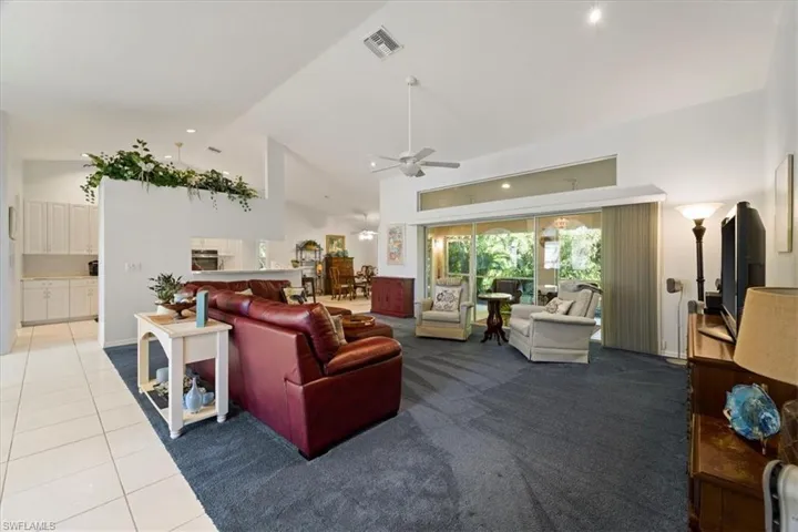 Carpeted living room with high vaulted ceiling and ceiling fan