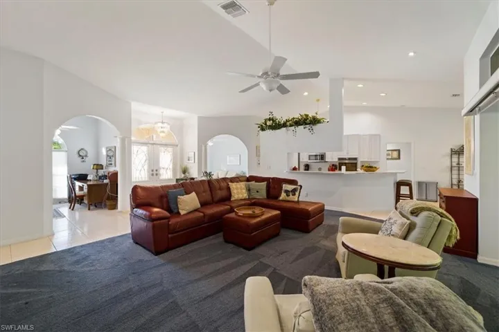 Tiled living room featuring high vaulted ceiling and ceiling fan