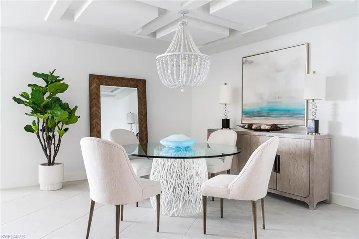 Dining area featuring coffered ceiling, a chandelier, light tile patterned floors, and beamed ceiling