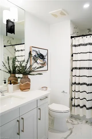 Bathroom with light marble finish flooring, vanity, and shower / bath combination with curtain