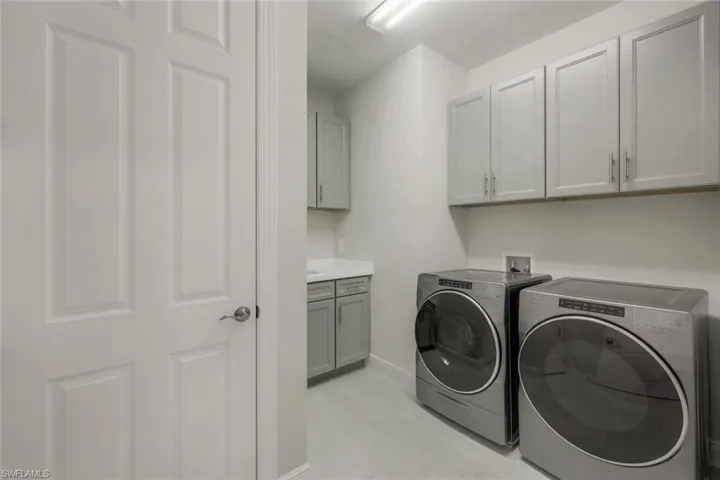 Laundry room with upgraded appliances, cabinets, and sink