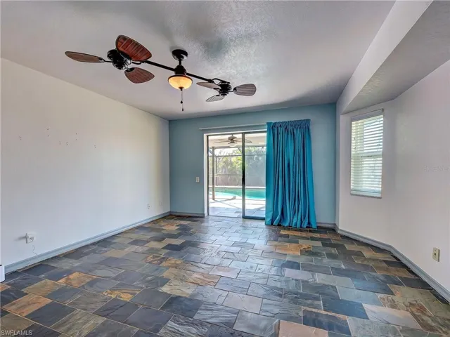 Spare room with dark stone finish flooring, a sunroom, ceiling fan, healthy amount of natural light, and a textured ceiling