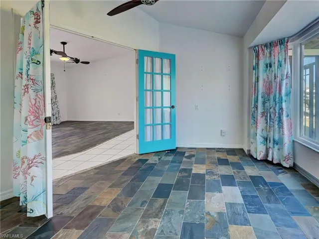 Spare room featuring a ceiling fan, lofted ceiling, and dark stone finish floors
