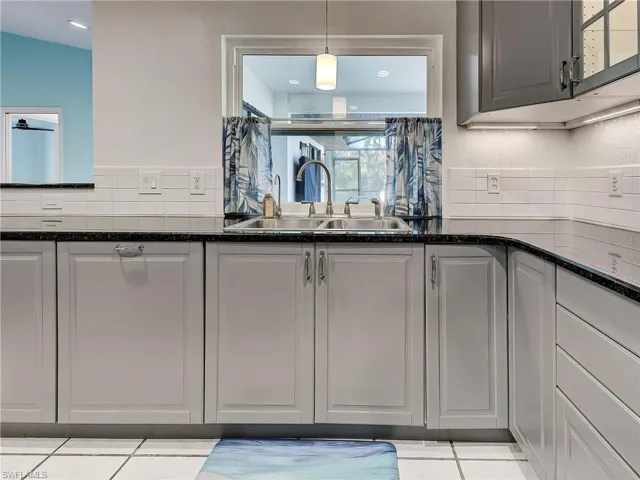 Kitchen with decorative light fixtures, dark stone counters, and a textured wall