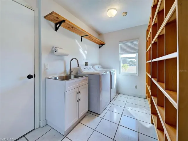 Laundry room with washing machine and clothes dryer and light tile patterned floors