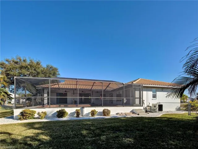 Back of property with a sunroom, a lanai, a yard, and a tiled roof
