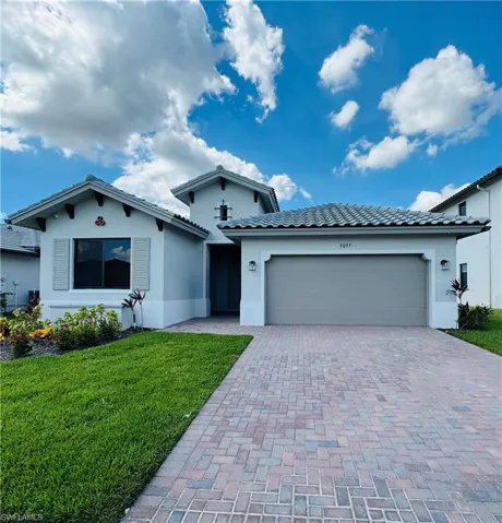 Ranch-style house with stucco siding, decorative driveway, and a front lawn