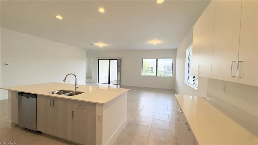 Kitchen with open floor plan, dishwasher, recessed lighting, light tile patterned floors, and a kitchen island with sink