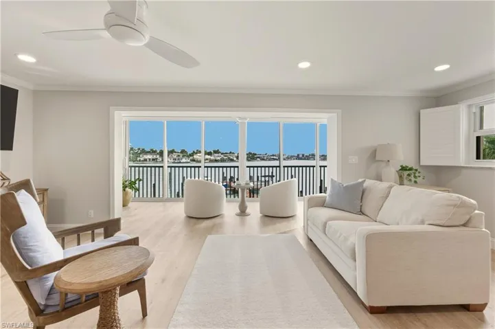 Living area featuring healthy amount of natural light, light vinyl floors, recessed lighting, ornamental molding, and a water view