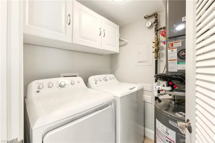 Laundry room with cabinet space, water heater, electric panel, and washer and clothes dryer