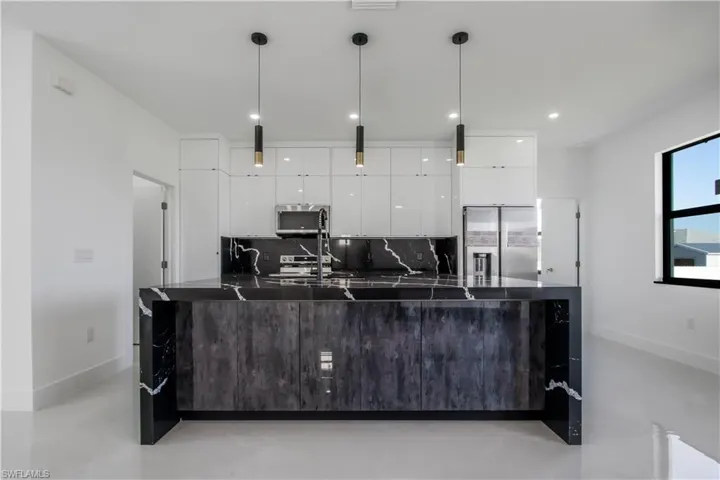 Kitchen with decorative backsplash, appliances with stainless steel finishes, white cabinetry, dark countertops, and modern cabinets